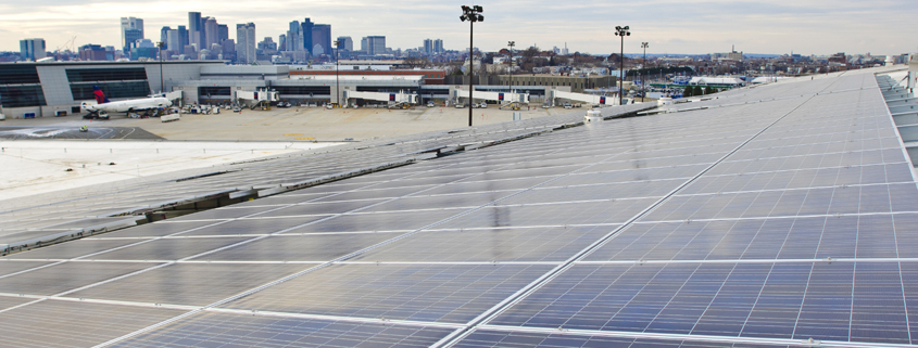 Daytime view of Logan Airport in Boston with solar panels on the roof of a terminal in the foreground