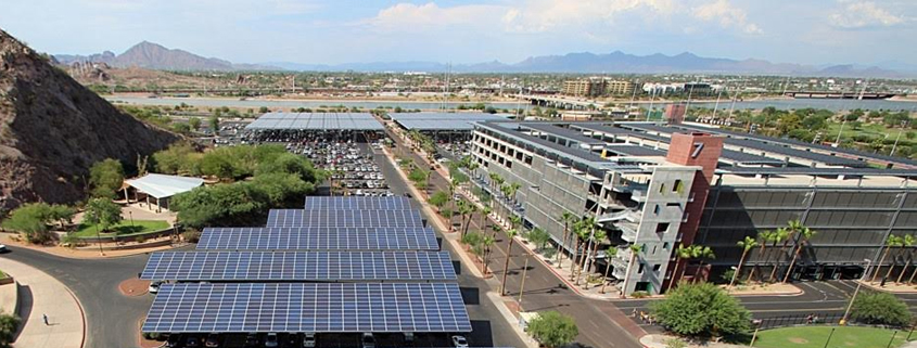 Daytime aerial view of Arizona State University parking areas showing solar carport installations and panels on the top level of a parking garage
